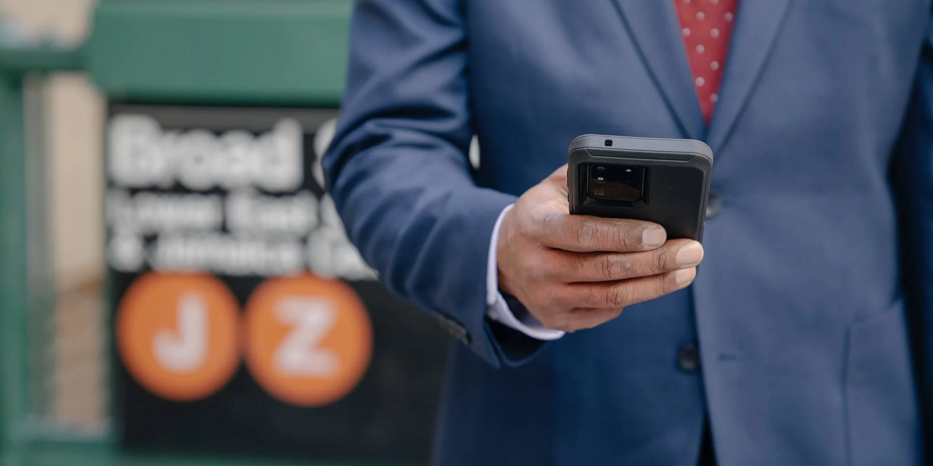 person in blue suit jacket holding a black smartphone