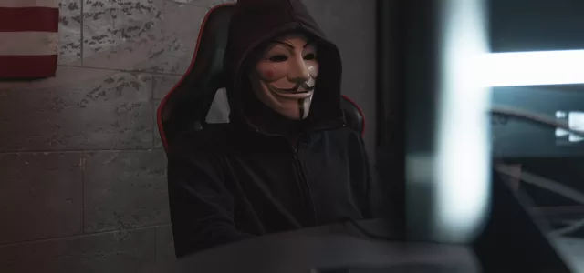 person in black hoodie hacking a computer system