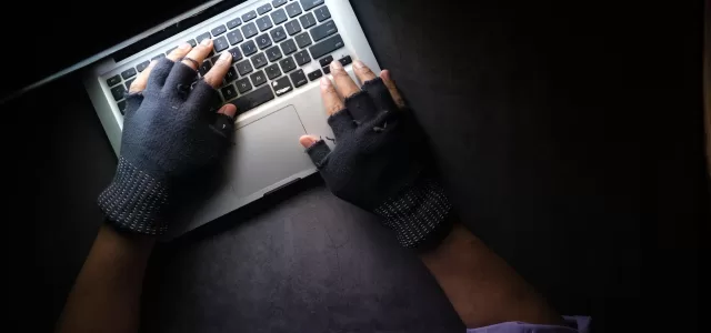 a person typing on laptop while wearing a fingerless gloves