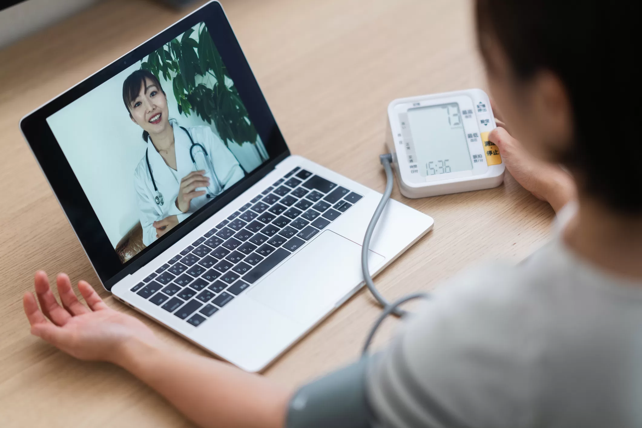 Woman measuring her blood pressure while consulting with doctor via telemedicine at home