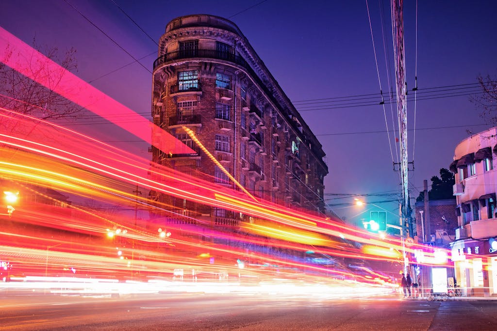 A dynamic long exposure of traffic light streaks against historic Shanghai architecture at night.