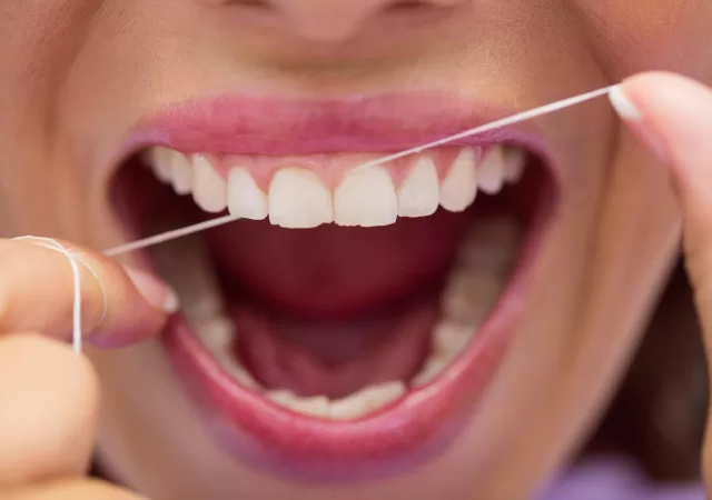 Close up of female patient flossing her teeth in dental clinic