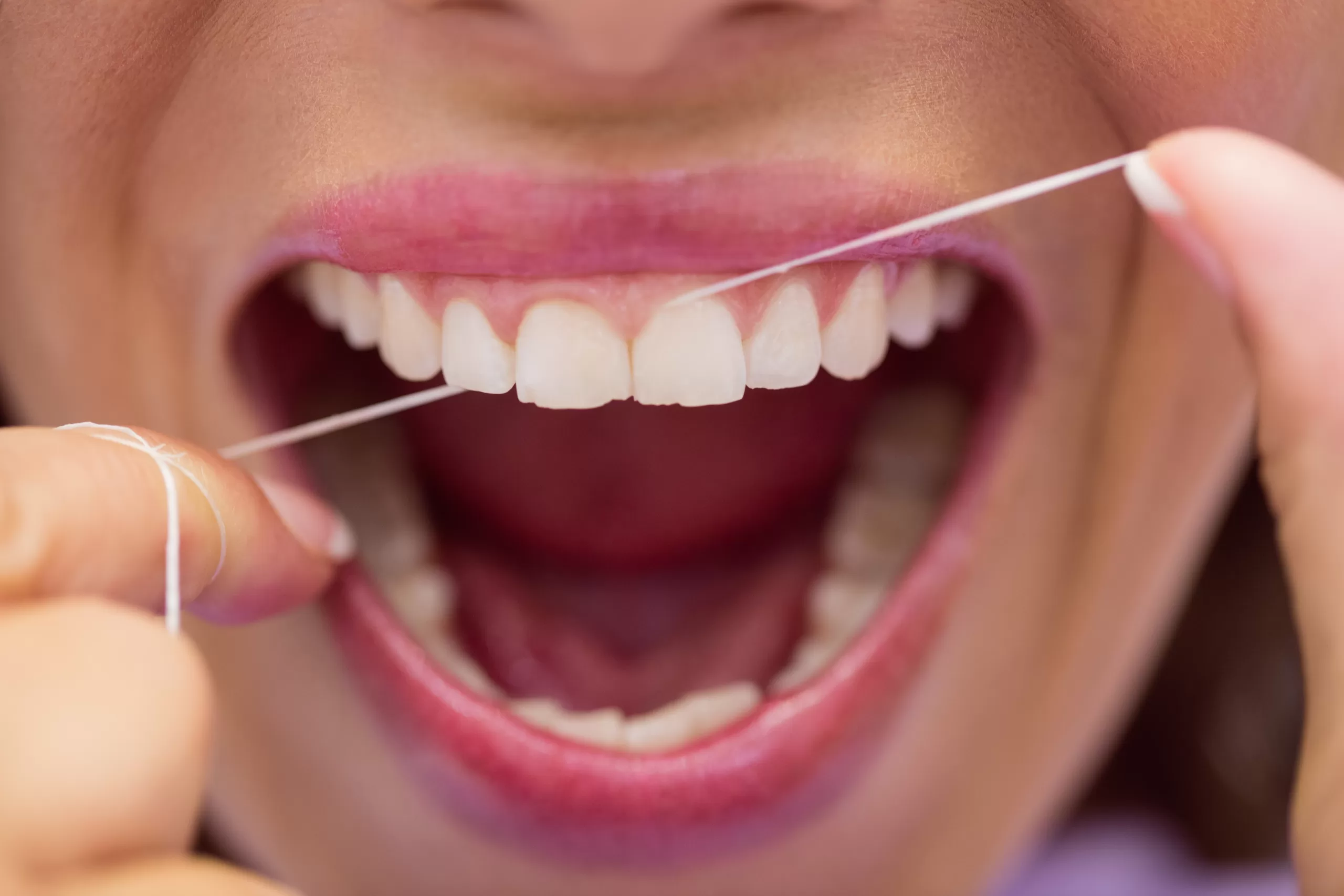 Close up of female patient flossing her teeth in dental clinic